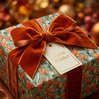 Elegant floral wrapping paper with a burnt orange velvet bow and gift tag by Wrapped Studios.