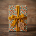 Autumn floral wrapping paper by Wrapped Studios with sage green, orange flowers, and a mustard velvet bow.