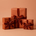 Three gifts wrapped in solid copper paper with luxurious velvet ribbons and bows.
