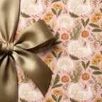 Thanksgiving wrapping paper with turkeys and pumpkins, tied with a gold satin bow by Wrapped Studios.