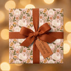 Thanksgiving wrapping paper with a turkey and pumpkin pattern, tied with a rust bow by Wrapped Studios.