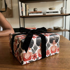 Luxury wrapping paper by Wrapped Studios featuring illustrated Black women, red florals, and a black velvet bow.
