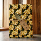 Vintage banana wrapping paper with twine bow and Cheers tag on a gift box, by Wrapped Studios.