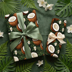 Wrapped Studios tropical coconut gift wrap in deep green with lush foliage & white flowers, tied with sage & cream ribbons.