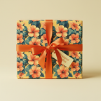 Square gift box wrapped in yellow floral wrapping paper with coral hibiscus flowers and matching ribbon.