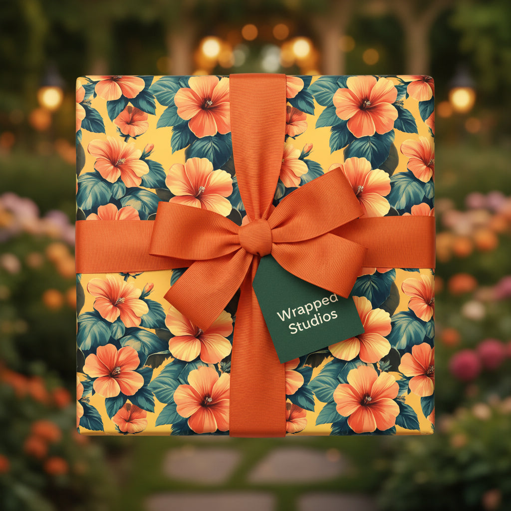 Square gift box wrapped in floral wrapping paper with orange ribbon and bow.