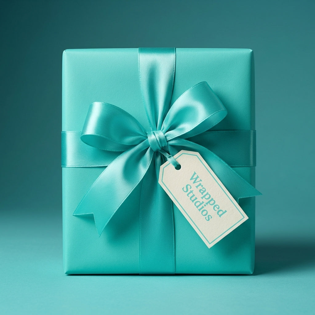 Elegant gift wrapped in solid teal wrapping paper with a satin bow and tag.