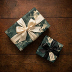 Vintage forest luxury gift wrap on boxes with cream and black satin bows by Wrapped Studios.