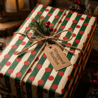 Rustic Christmas wrapping paper with green stripes and red dots on a gift box by Wrapped Studios.