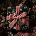 Luxury dark floral wrapping paper with a dusty rose velvet bow by Wrapped Studios.