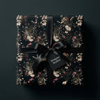 Luxury dark floral wrapping paper on a gift box with a black satin ribbon, by Wrapped Studios.