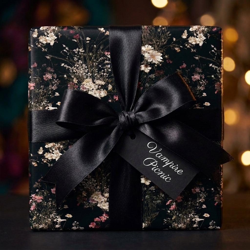 Dark gothic floral wrapping paper with a black satin bow and gift tag by Wrapped Studios.