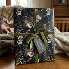 Vintage floral wrapping paper in a dark botanical print, tied with green velvet ribbon by Wrapped Studios.