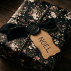 Luxury dark floral Christmas wrapping paper by Wrapped Studios, featuring a rustic Noel gift tag and black wax seal.