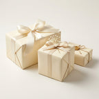 Three vanilla cream colored gift boxes with decorative ribbons on a light background