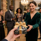 Woman receiving a present with luxury Christmas wrapping paper and a gold bow. Wrapped Studios.