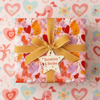 Playful pink and red abstract heart wrapping paper with a gold ribbon, perfect for birthday or Valentine's Day gifts.