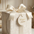Luxury religious wrapping paper with vintage angel pattern, cream satin bow, and Wrapped Studios gift tag.