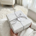 Elegant angel wrapping paper with a silver ribbon and blessings tag, perfect for baptisms by Wrapped Studios.