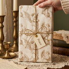 Hand holding gift in vintage angel Christmas wrapping paper with gold twine by Wrapped Studios.