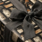 Close-up of apothecary wrapping paper featuring potion bottles, tied with a charcoal gray frayed ribbon.