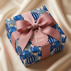 Luxury blue floral wrapping paper with a pink bow and 'With Love' tag by Wrapped Studios.