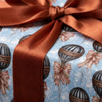 Luxury vintage wrapping paper with blue hot air balloon pattern and rust satin bow by Wrapped Studios.