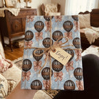 Vintage hot air balloon wrapping paper by Wrapped Studios, tied with rustic twine and an Enjoy gift tag.