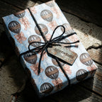 Vintage hot air balloon wrapping paper with black twine and an adventure tag on a gift box by Wrapped Studios.