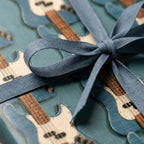 Blue bass guitar wrapping paper with a matching fabric ribbon bow, music gift wrap by Wrapped Studios.