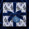 Luxury floral wrapping paper with blue lupines and a velvet bow. Botanical gift wrap by Wrapped Studios.