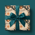 Vintage celestial wrapping paper with a sun and moon design and teal satin ribbon by Wrapped Studios.