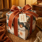 Vintage celestial gift wrap with sun and moon illustrations and a rust ribbon bow by Wrapped Studios.