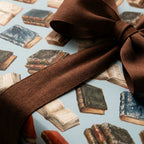 Vintage book wrapping paper with a brown ribbon bow for book lovers, by Wrapped Studios.