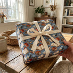 Blue bookish wrapping paper with a vintage book pattern and cream bow by Wrapped Studios.