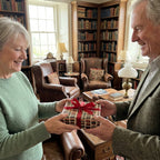Older couple exchanging a gift in vintage plaid wrapping paper with a red ribbon by Wrapped Studios.