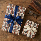 Vintage book wrapping paper by Wrapped Studios on gifts with elegant navy and cream bows.