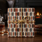 Vintage book wrapping paper with gold rope bow on a gift box, by Wrapped Studios.
