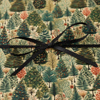 Gift wrapped in forest green tree pattern paper with a sleek black ribbon.