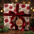 Elegant poinsettia Christmas wrapping paper with a red velvet bow by Wrapped Studios.