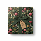 Elegant Christmas gift wrap featuring a dark botanical pattern with pink and gold ornaments, tied with a deep green ribbon and "To You" tag.