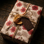 Vintage Christmas wrapping paper with red poinsettia pattern on a rustic gift box by Wrapped Studios.