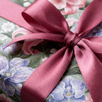 Luxury floral wrapping paper with purple orchids and a dusty rose satin bow by Wrapped Studios.