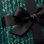 Luxury emerald green botanical wrapping paper with a black satin ribbon bow by Wrapped Studios.