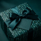 Dark green botanical luxury gift wrap with a satin ribbon and embossed tag by Wrapped Studios.