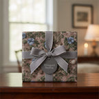 Elegant floral wrapping paper with blue blossoms, tied with a silver ribbon and bow on a gift box.