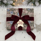 Elegant Christmas gift with floral wrapping paper, burgundy velvet ribbon, and "Happy Holidays" star tag.