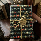 Luxury vintage apothecary wrapping paper, dark with colorful jars, gold twine & 'Open Me' tag. Wrapped Studios.
