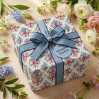 Elegant floral wrapping paper by Wrapped Studios on a gift box with a blue ribbon and spring flowers.