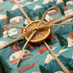 Vintage camper wrapping paper with mountains, tied with rustic twine and a dried orange slice by Wrapped Studios.